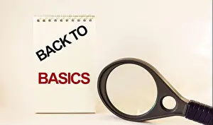 BACK TO BASIC, text written on notepad and white background, near a magnifying glass