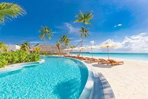 Beach landscape. Luxurious beach resort with swimming pool and beach chairs or loungers under umbrellas with palm trees, vacation, travel holiday