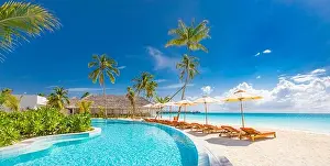 Beach landscape. Luxurious beach resort with swimming pool and beach chairs or loungers under umbrellas with palm trees, vacation, travel holiday