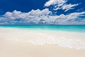 Beach and tropical sea. Relaxing waves splashing with foam on soft white sand. Endless seascape and horizon. Calmness nature landscape under blue sky