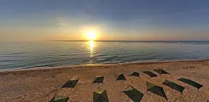 Beauty Day Prints: Beach umbrellas at sunrise. Sea current swims against the waves on the beautiful sea