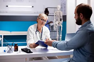 Patiently Prints: Bearded man sits with elderly doctor in clinic office
