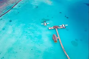 Beautiful aerial view of Maldives jetty seaplane top view with wooden boat Dhoni and tropical beach, jetty over wonderful blue sea. Luxury travel