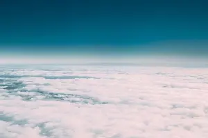Beautiful Aerial View Of Sunny Clear Sky Over White Fluffy Clouds From Height Flight Of Plane. Bright White And Blue Colors Of Sunny Sky