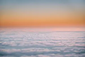 Beautiful Aerial View Of Sunny Clear Sky Over White Fluffy Clouds From Height Flight Of Plane. Bright Orange And Yellow Colors Of Sunny Sky. Natural B