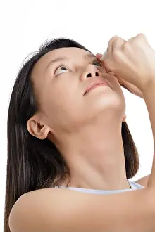 Medicament Prints: Beautiful Asian woman using eyedrops to relieve dry eyes isolated on a white background with copy space