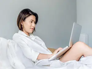 Typing Prints: Beautiful Asian women with short hair wearing white shirt working with laptop computer on wooden bed in white bedroom
