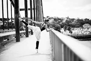 Toes Prints: A beautiful blond ballerina is giving a kick whilst leaning against the bridge railing over the river