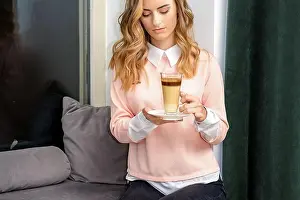 Latte Prints: Beautiful caucasian young woman with long wavy blonde hair holding and drinking latte from a glass cup
