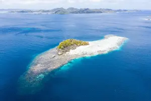 Misool Prints: A beautiful coral reef surrounds a small island amid the tropical seascape in Raja Ampat