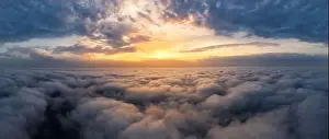 Beautiful dramatic sunset sky above fluffy clouds early in the morning. Drone view