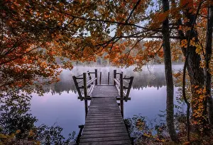Beautiful fall colors with wooden pier and peaceful lake at autumn morning in Finland