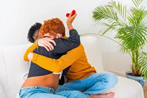 Beautiful gay couple being romantic on the sofa, lgbt concept, man asking for marriage with a ring