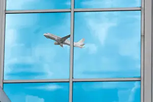 Mode Of Transport Prints: Beautiful glass building facade with reflections of an airplane during startup