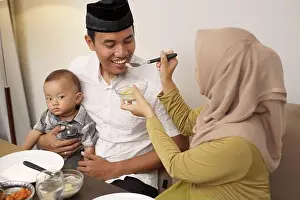 Veil Prints: beautiful hijab woman serving some food for her husband during breaking the fast in the evening