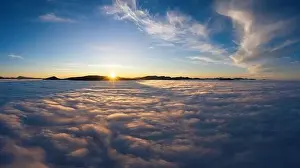 Beautiful landscape with high mountains sticking out of fluffy clouds at sunrise from aerial view