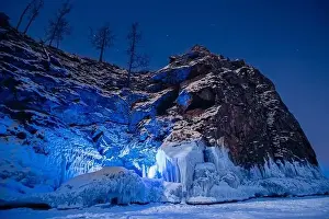 Beautiful landscape island Shaman Stone winter lake Baikal with transparent cracked blue ice. Concept travel Russia