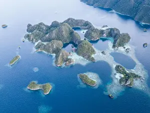 Beautiful limestone islands rise from the calm seas of Raja Ampat, Indonesia. This remote region is known for its extraordinary marine biodiversity