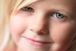 Green Eyes Prints: A beautiful little blonde girl with bright green eyes smiling into the camera, close up