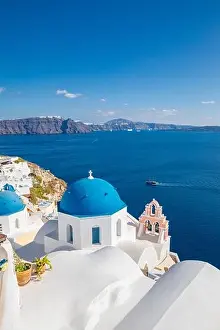 Beautiful Oia town on Santorini island, Greece. Traditional white architecture and greek orthodox churches with blue domes over Caldera, Aegean sea