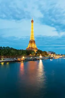 Beautiful Paris view of illuminated Eiffel tower along Seine river at dusk, Paris, France
