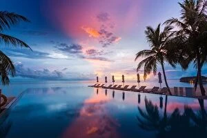 Images Dated 9th May 2018: Beautiful poolside and sunset sky with palm trees. Luxury tropical beach landscape