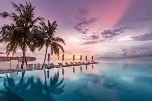 Images Dated 9th May 2018: Beautiful poolside and sunset sky with palm trees. Luxury tropical beach landscape