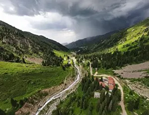 Summer Hill Prints: Beautiful scenery of the mountains with green hill and river in at storm rain cloudy sky and resort in Almaty