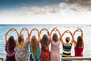 Red Sea Prints: beautiful seven girls from the backside doing a heart with the hands looking at the ocean waiting the sunset