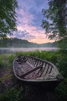 Beautiful sunrise in tranquil lake at summer evening in Finland with wooden boat