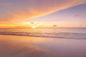 Beautiful sunset on the beach and sea. Tropical beach at beautiful sunset. Nature background. Exotic landscape, shore, coast, calm waves, soft sand