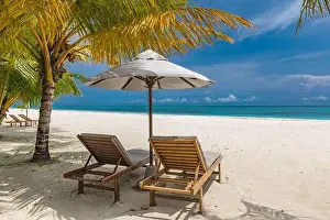 Beautiful tropical beach. White sand and coco palms chairs, umbrella travel tourism, amazing beach landscape. Luxury island resort vacation or holiday