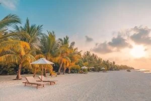 Images Dated 13th December 2018: Beautiful tropical sunset landscape, two sun beds, loungers, umbrella under palm tree