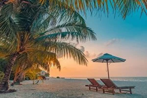 Images Dated 13th December 2018: Beautiful tropical sunset landscape, two sun beds, loungers, umbrella under palm tree