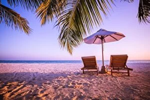 Images Dated 5th January 2017: Beautiful tropical sunset scenery, two sun beds, loungers, umbrella under palm tree