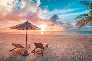 Images Dated 2nd June 2019: Beautiful tropical sunset scenery, two sun beds, loungers, umbrella under palm tree