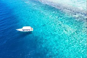 Beautiful turquoise ocean water boat top view aerial photo. Aerial view speed boat in the sea. Exotic sea lagoon, snorkel adventure, tropical ocean