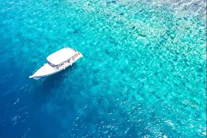 Beautiful turquoise ocean water boat top view aerial photo. Aerial view speed boat in the sea. Exotic sea lagoon, snorkel adventure, tropical ocean