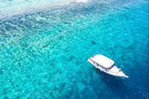 Beautiful turquoise ocean water boat top view aerial photo. Aerial view speed boat in the sea. Exotic sea lagoon, snorkel adventure, tropical ocean