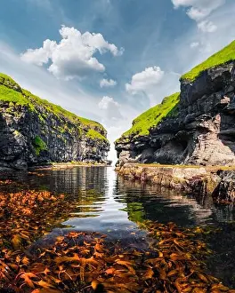Beautiful view of dock or harbor with clear water and red seaweed in Gjogv village, Eysuroy island, Faroe Islands, Denmark. Landscape photography