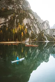 Beautiful view of famous Lago di Braies with young man in kayak at sunrise in fall, Dolomites, Italy