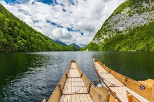 Beautiful view of traditional wooden rowing boat on scenic. Summer mountain lake pass scenic morning light at sunrise clouds over blue sky green trees