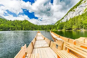 Beautiful view of traditional wooden rowing boat on scenic. Summer mountain lake pass scenic morning light at sunrise clouds over blue sky green trees
