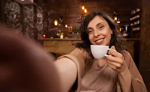 Cafeteria Prints: Beautiful woman using mobile phone to take a selfie during her work in a coffee shop