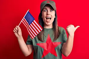 Optimistic Prints: Beautiful woman wearing t-shirt with red star communist symbol holding united states flag pointing thumb up to the side