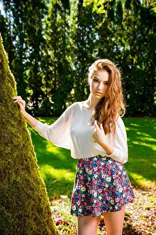 A beautiful young girl poses for a fashion style portrait outdoors at a park with natural lighting