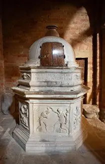 A beautifully carved stone baptismal font stands in warm light showing religious reliefs