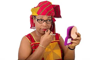 Maturity Prints: beauty, makeup and elderly people concept in red african outfit - smiling senior woman applying lipstick on her lips