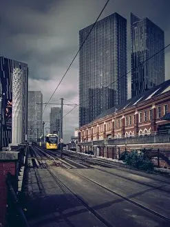 Deansgate Square Prints: A Bee Network tram in Manchester against the backdrop of Deansgate Square tower skyscrapers with dark cloudy sky