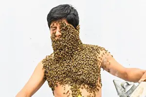 Beekeeper covered by bees, he has the queen bee on his neck so all the bees stick to his body. surrealism